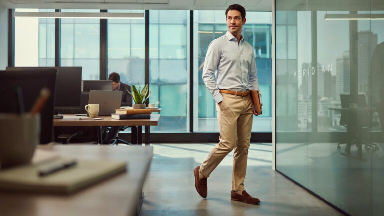 Professional man wearing beige chinos in a modern workplace, showcasing the Best Slim Fit Chinos for Men for Office Wear with a smart business-casual outfit.
