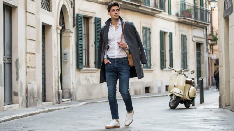 Best Skinny pants for Men in blue denim paired with a white shirt and gray overcoat for a stylish street fashion look.