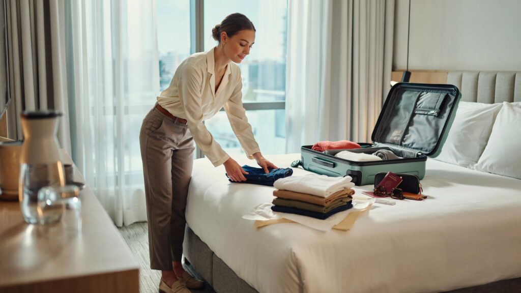 Traveler neatly folding pants into a suitcase, demonstrating How to fold pants for travel without wrinkles using space-saving and wrinkle-prevention packing techniques.